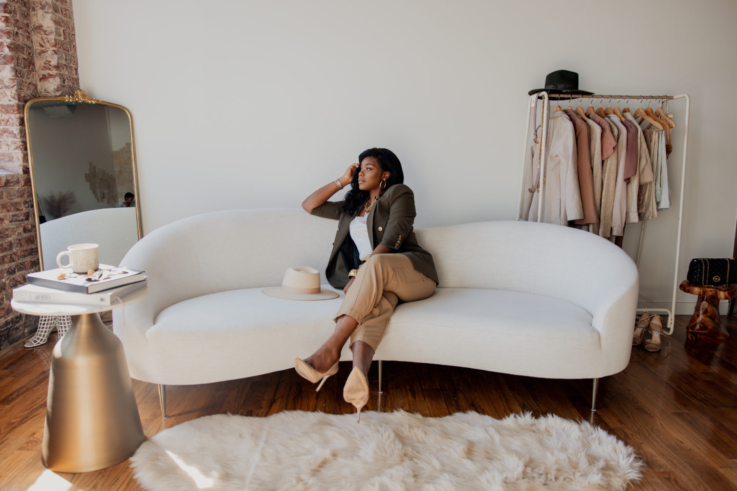 green blazer with cargo pants with nude pumps. Sitting on a white sofa in a studio