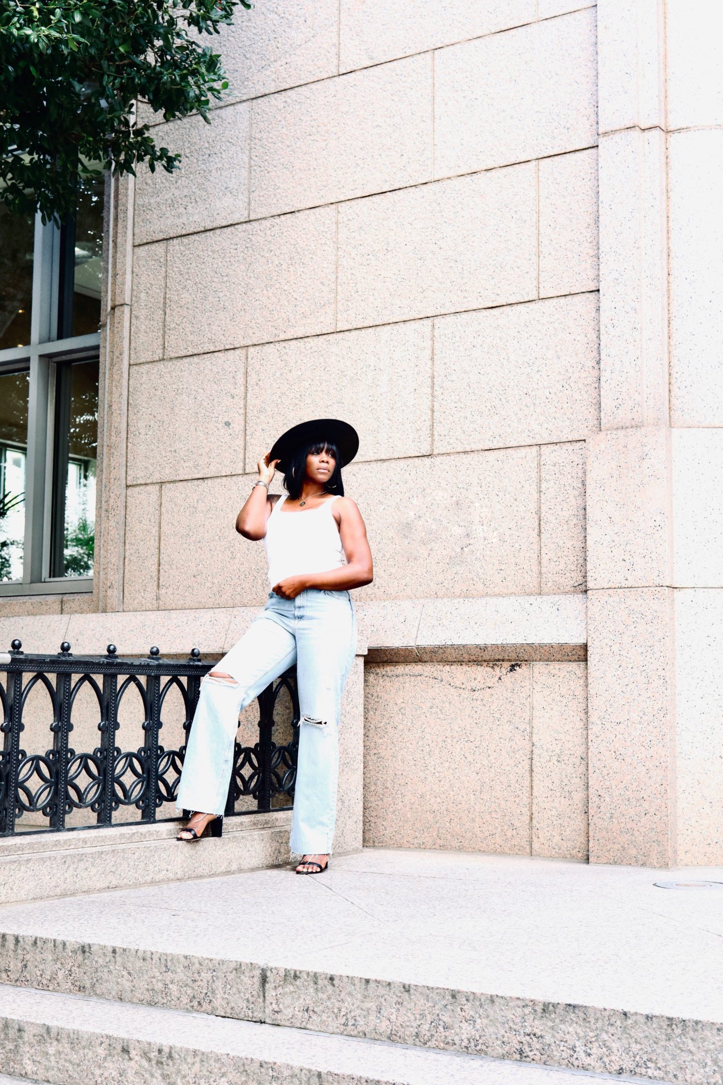 Black brixton straw hat with a white aritzia tank and zara jeans