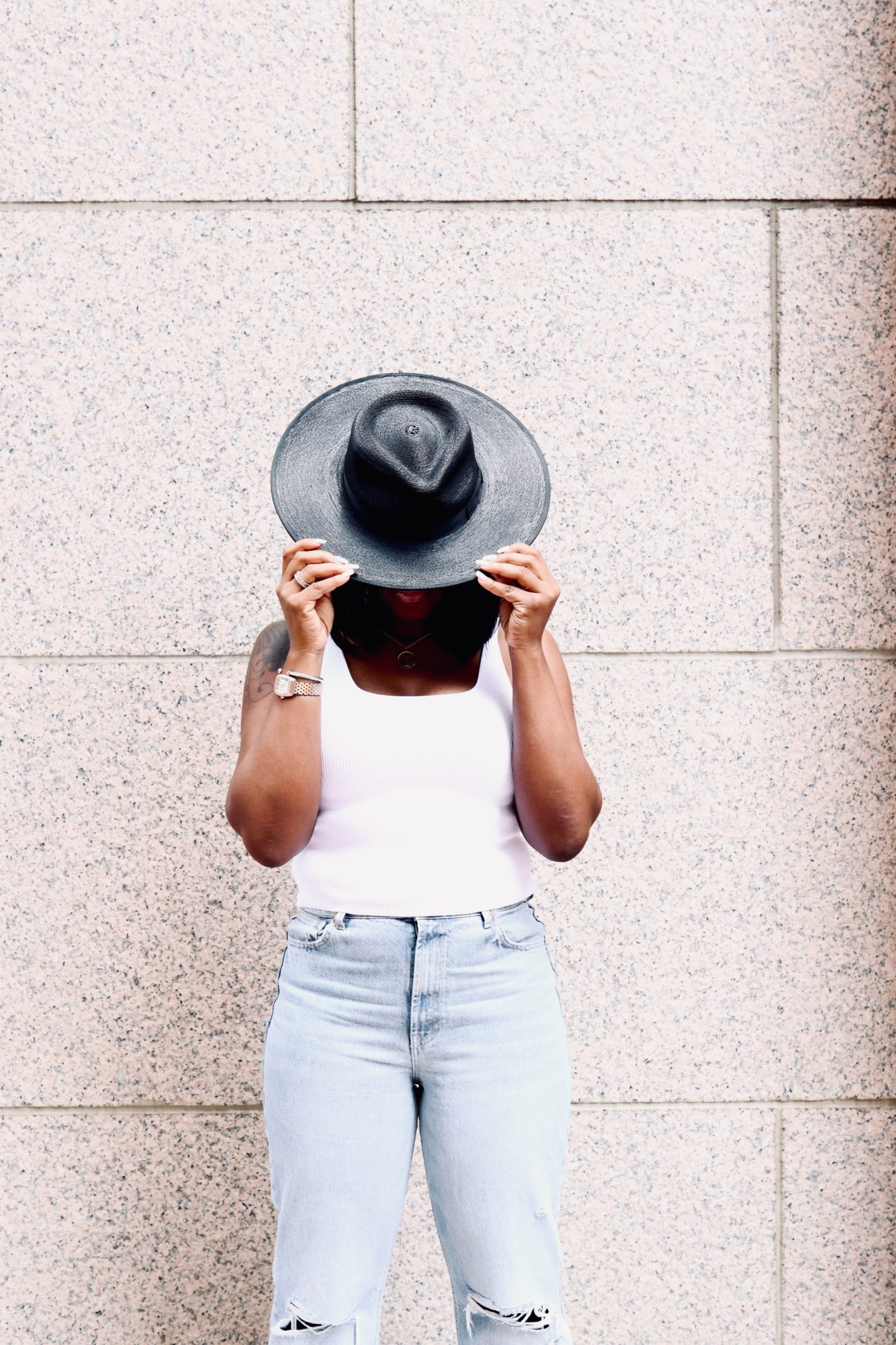 black straw hat with a white tank top and blue jeans