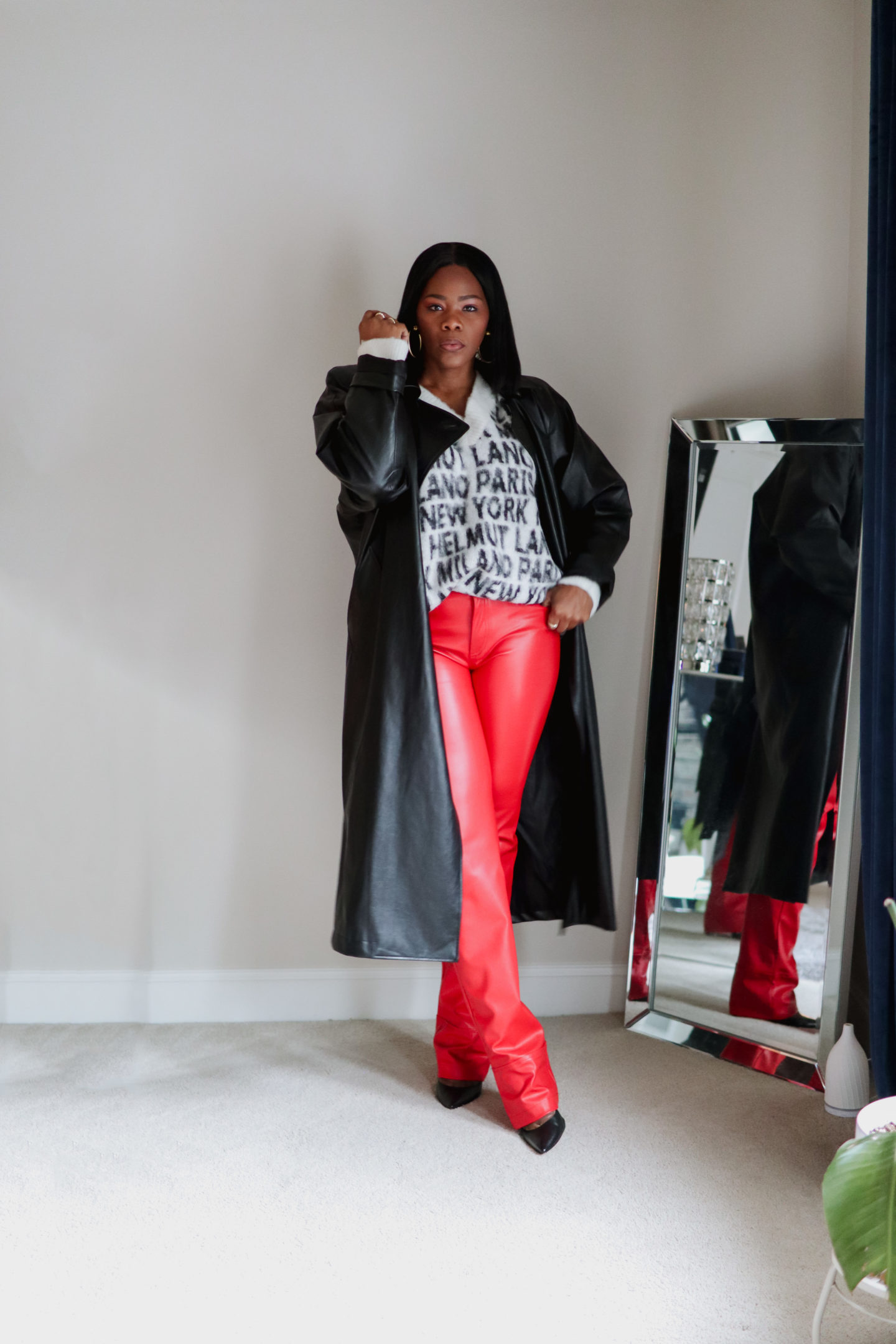 Red leather pants with a black and white sweater and an oversized faux leather trench